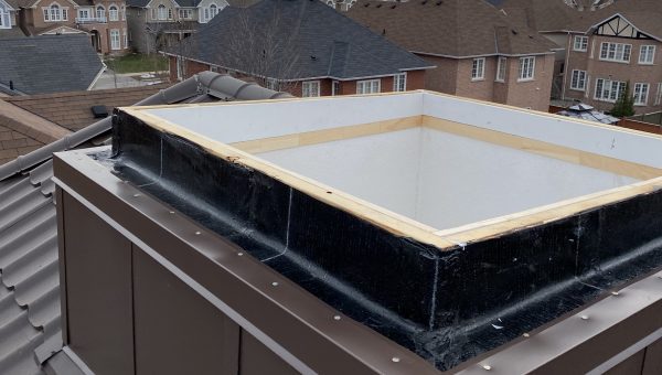 A square chimney structure sits on a residential rooftop, under a cloudy sky. A suburban neighborhood with rows of houses stretches into the distance, softly lit by evening light—an ideal scene for your trusted roofing company to handle any roof repairs.